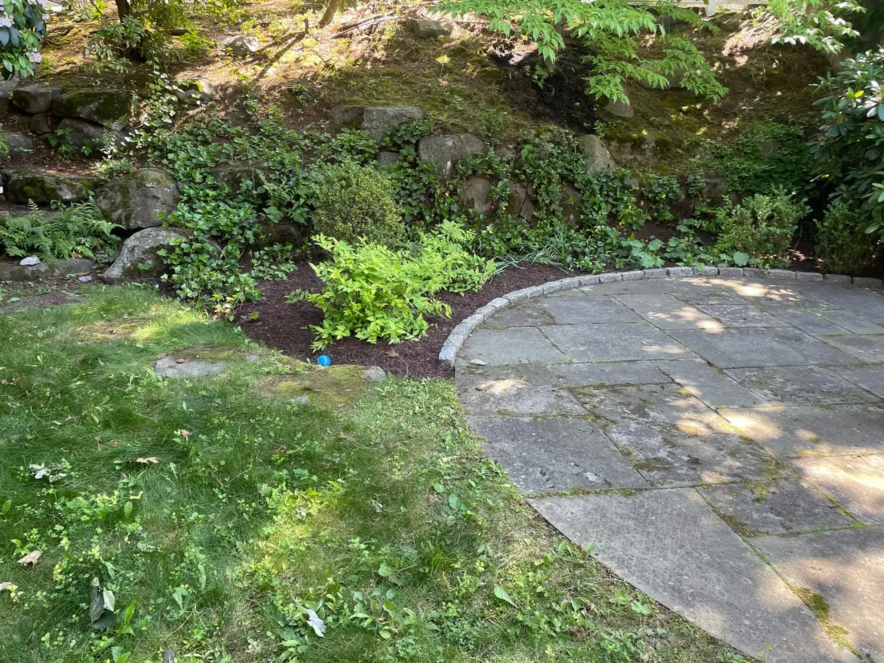 Curved stone patio beside fresh mulch and established planting